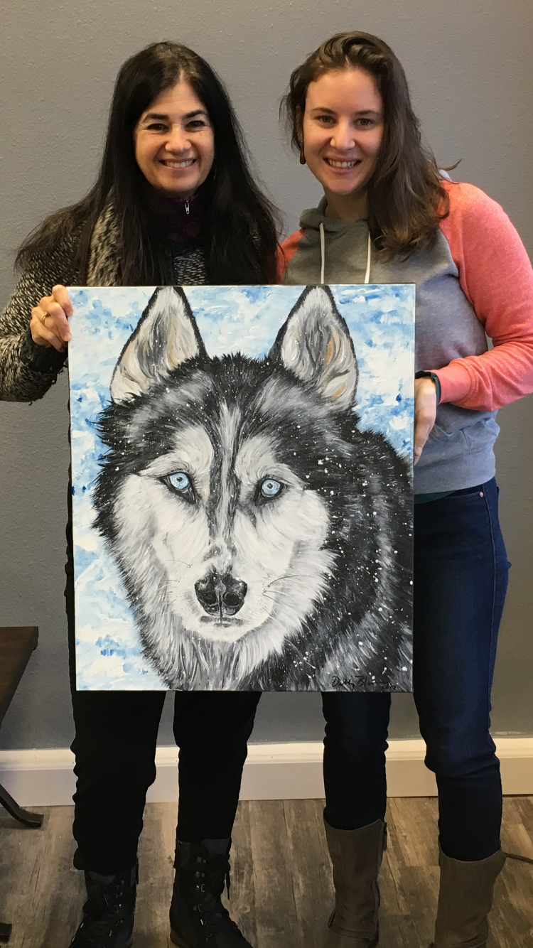 Two girls holding husky dog painting